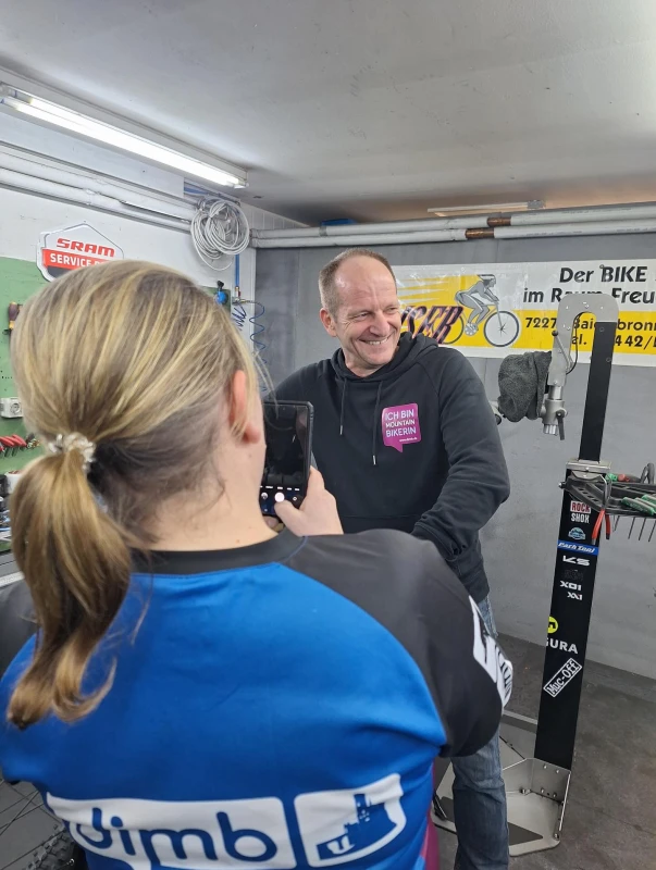Ein Mann in schwarzer Jacke und eine Frau in blauem Shirt in einer Fahrradwerkstatt.
