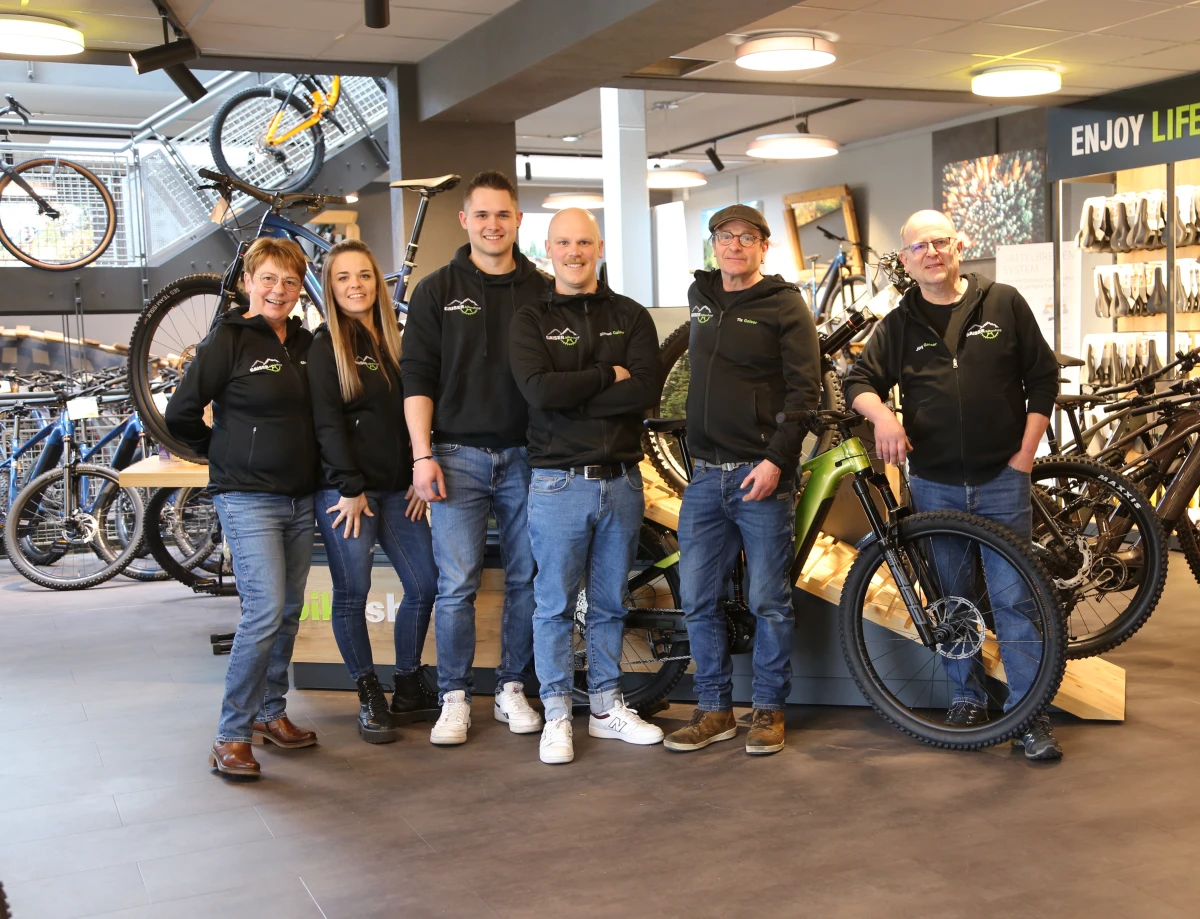 Gaiser Bikeshop Team in schwarzen Sweatern steht inmitten von Fahrr&auml;dern.