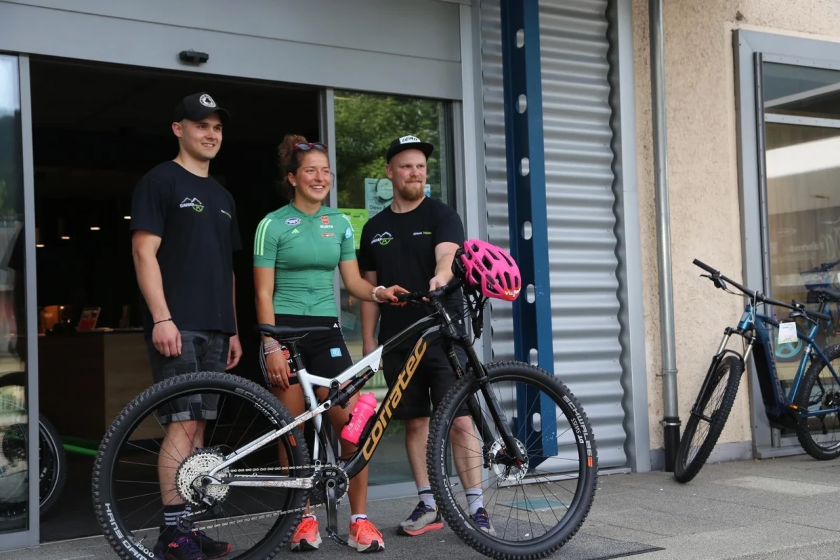 Drei Personen stehen vor einem Fahrradgesch&auml;ft mit Mountainbikes.