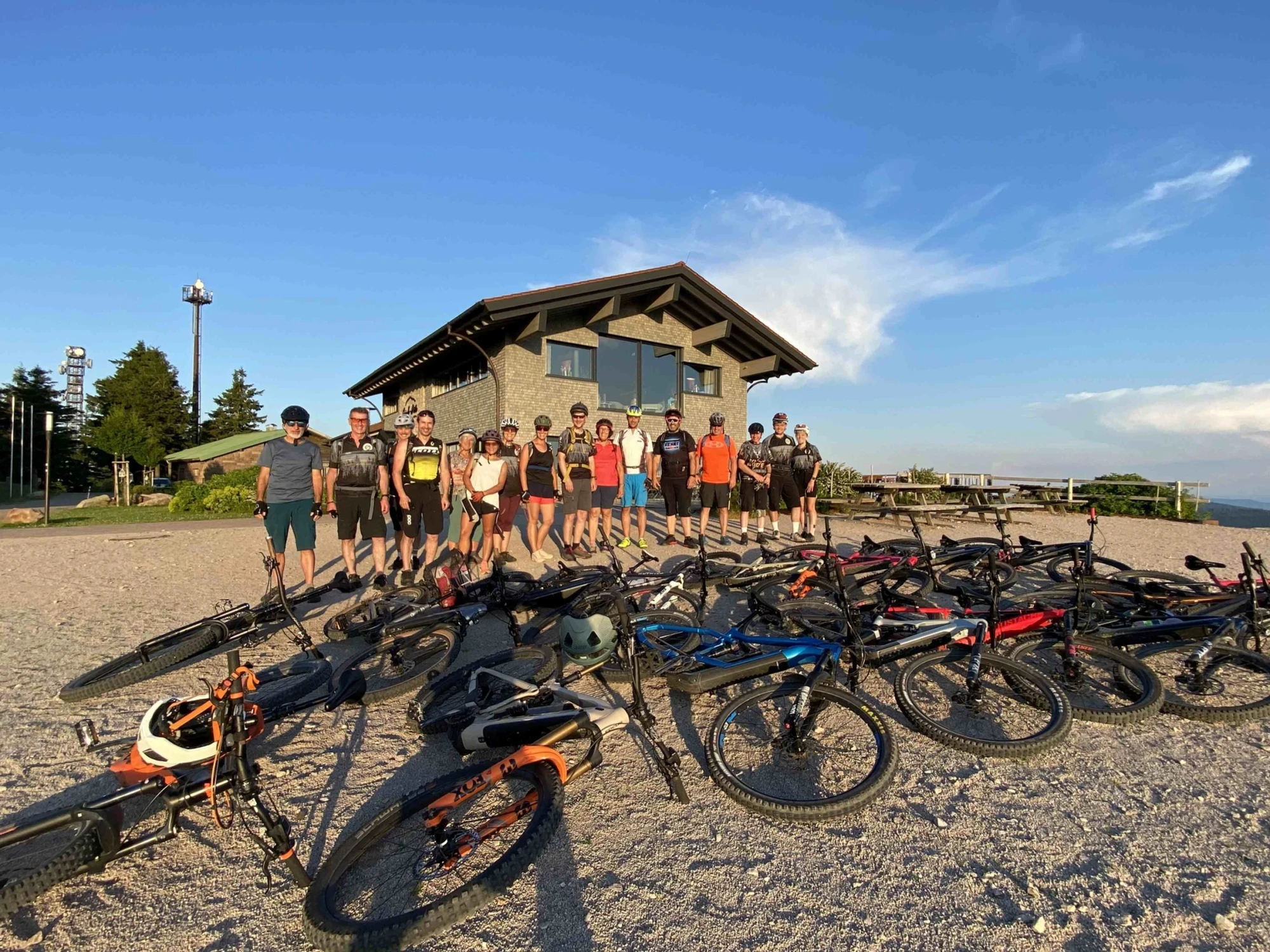 Gruppe von Radfahrern mit Fahrr&auml;dern vor einem Strandhaus bei Sonnenschein.