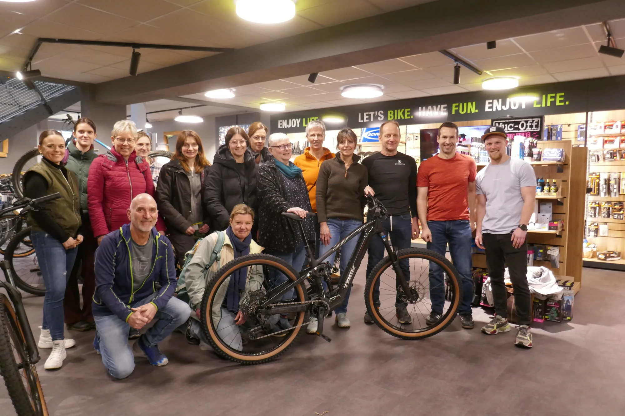 Gruppe von Menschen posiert zusammen mit einem Fahrrad in einem Fahrradgesch&auml;ft.