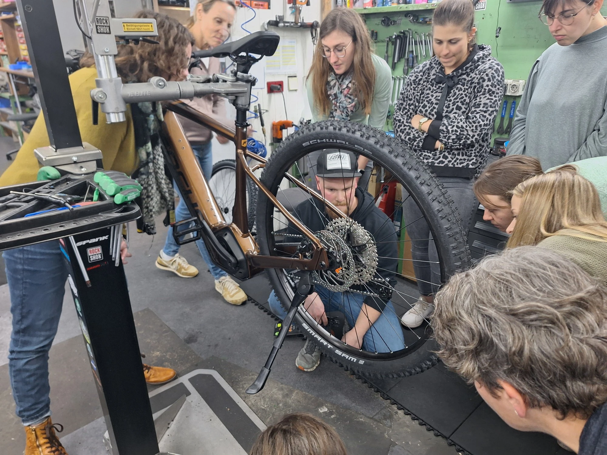 In der Fahrradwerkstatt mit Besuchern beim Reparieren eines Fahrrads.