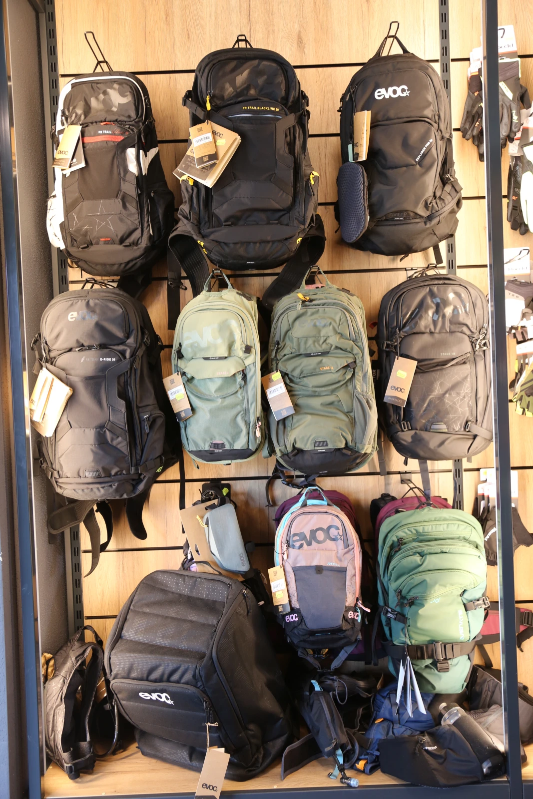 Fahrradhandschuhe und Zubeh&ouml;r in schwarzen und hellen Farben h&auml;ngen an einem Gitterdisplay im Laden.