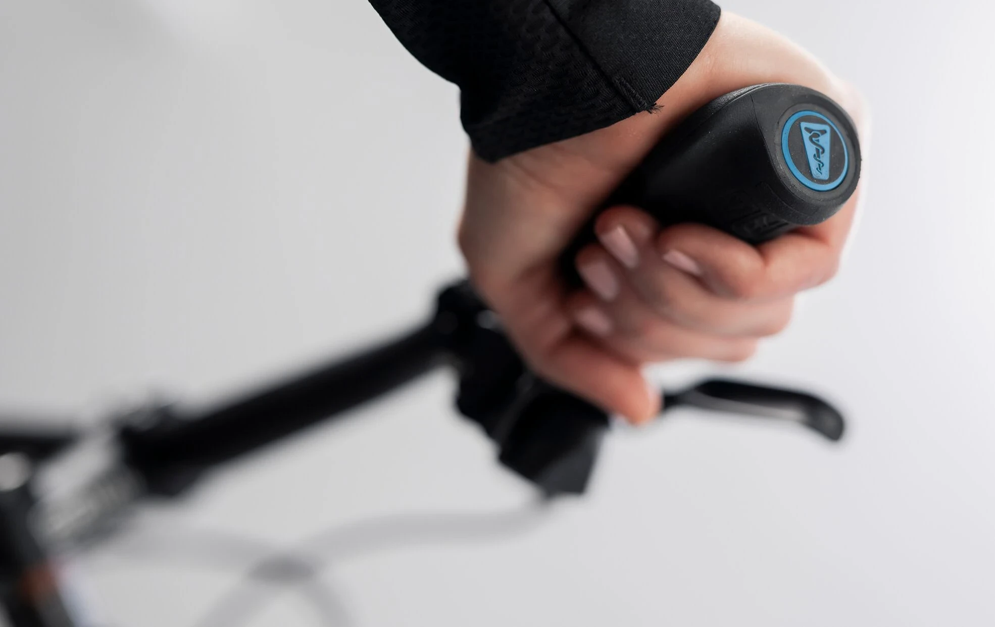 Hand h&auml;lt schwarzen Fahrrad-Schalthebel mit blauem Logo.