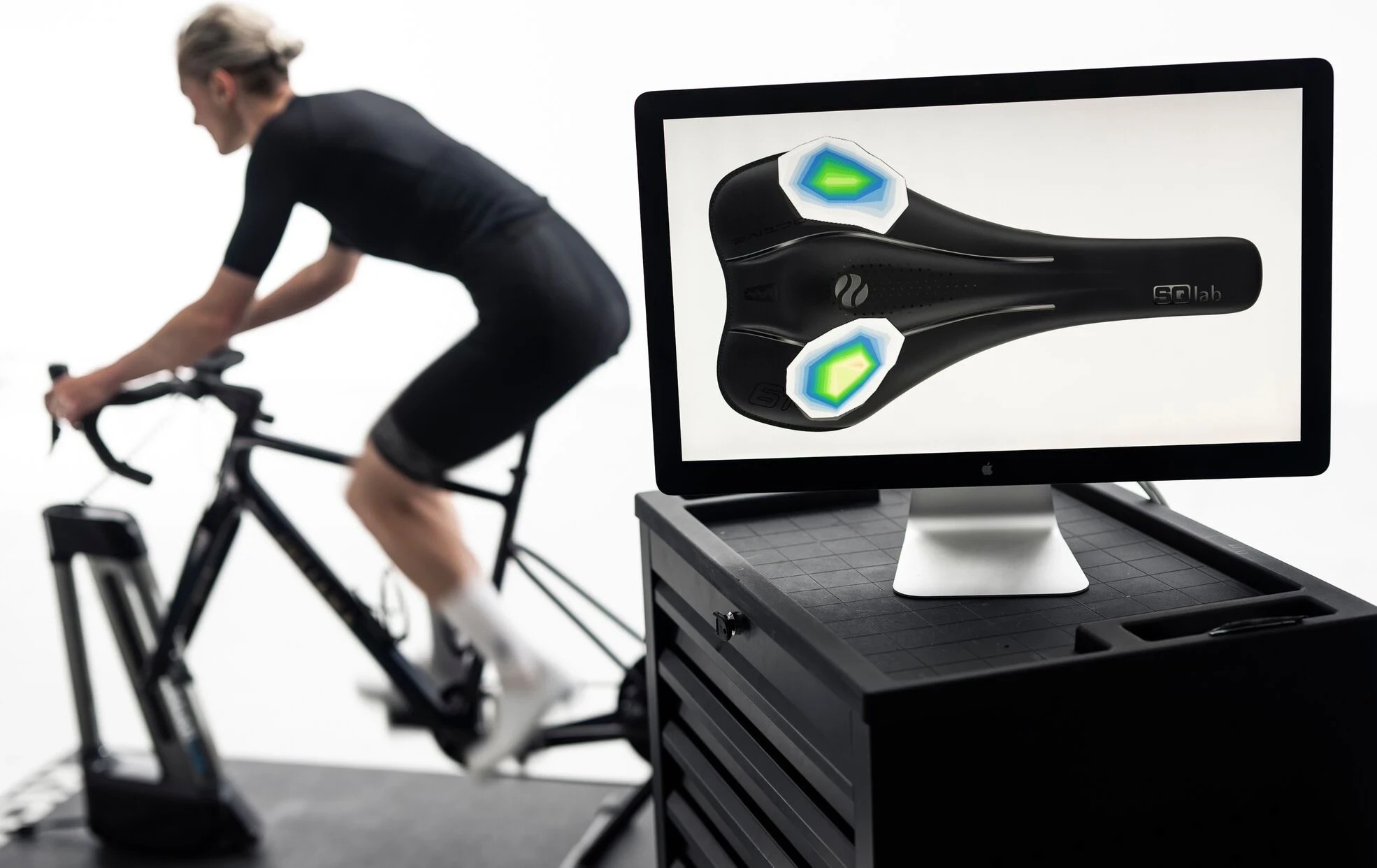 Fahrradfahrer auf Sattel mit Druckverteilungs-Analyse auf Monitor.