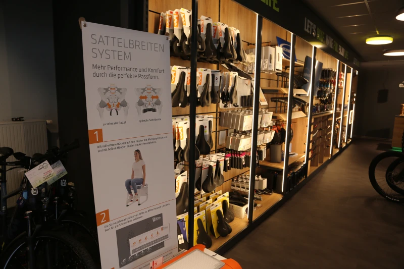 Schaufenster mit Fahrradsatteln in verschiedenen Farben und Gr&ouml;&szlig;en, daneben Infotafel zur Beratung.