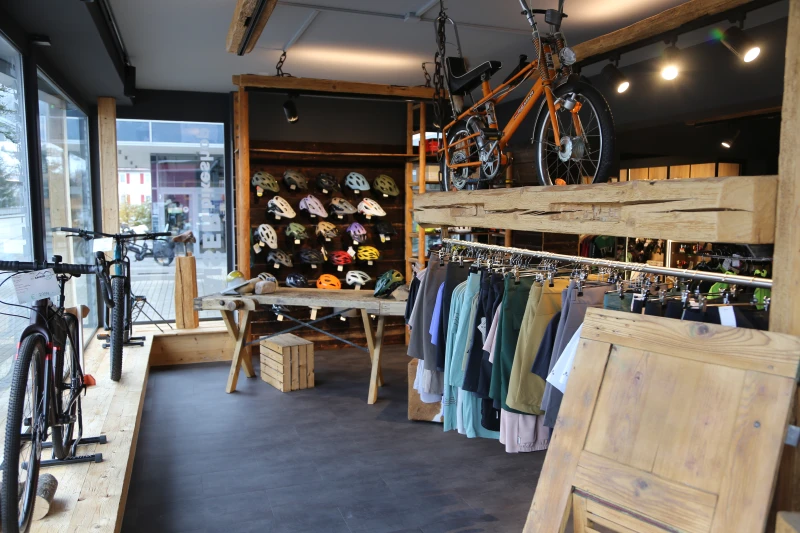 Verschiedene Fahrradhelme in unterschiedlichen Farben und Designs auf einer Wandhalterung im Fahrradladen.