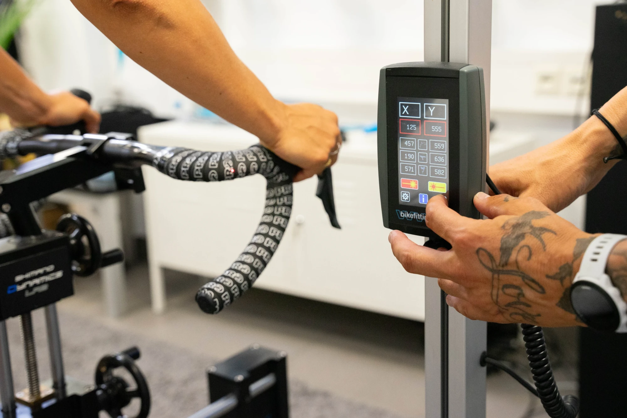 Mitarbeiter kalibriert ein Schaltwerk-Messinstrument an einem Rennrad mit Tretlager und Schaltung im Fahrradladen.