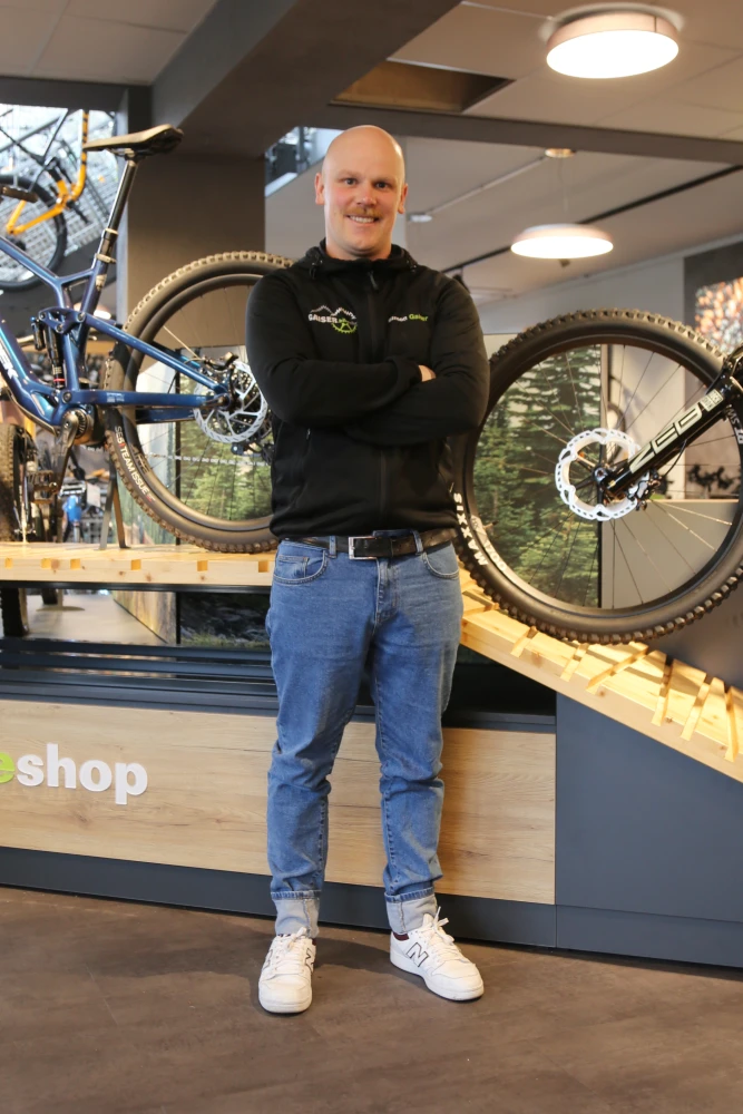 Ein Mann steht l&auml;chelnd in einem Fahrradladen vor ausgestellten Fahrr&auml;dern.