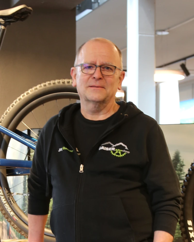 J&ouml;rg Gaiser in schwarzem Hoodie vor einem Fahrrad in der Bikeshop-Werkstatt.